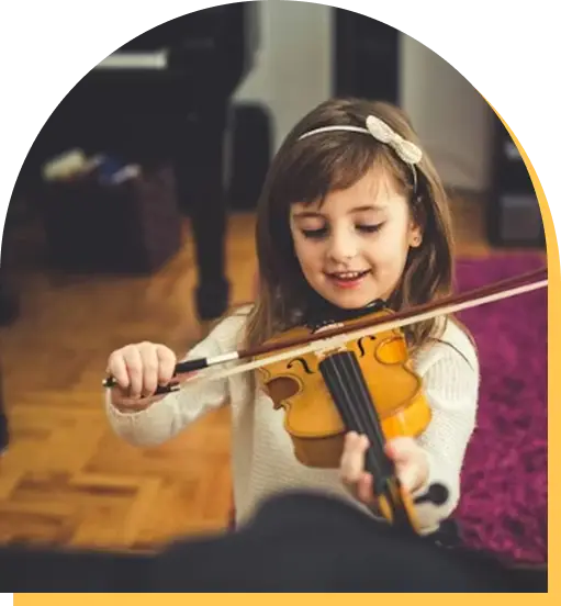 A young girl with light brown hair and a headband smiles while playing violin indoors on a wooden floor, with a purple rug and furniture in the background—capturing the joy of music lessons Westchase has to offer.
